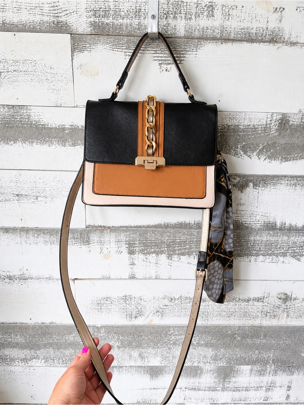 Black and Tan Top-Handle Crossbody Bag with Gold Chain Accent, and Scarf accent.